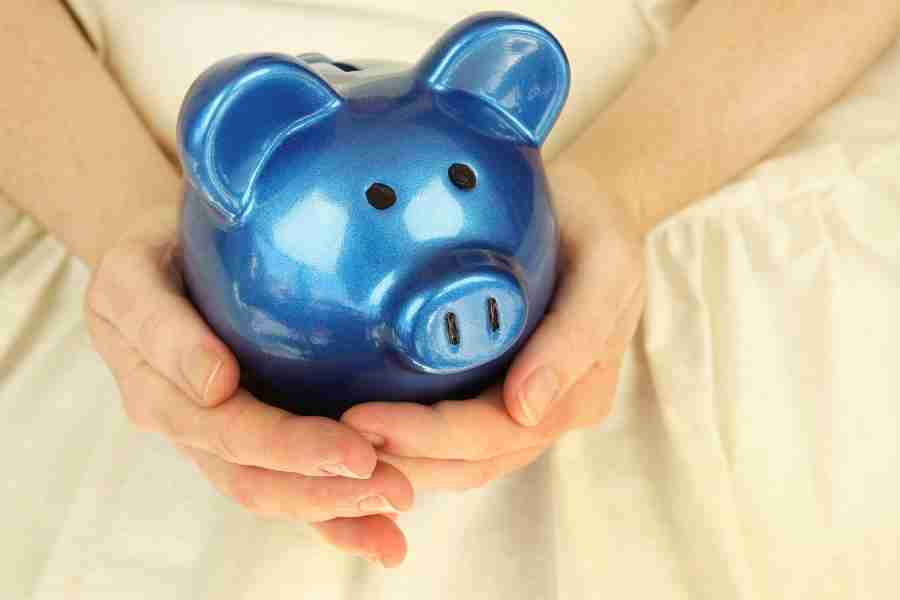 woman holding a blue piggy bank living on one income