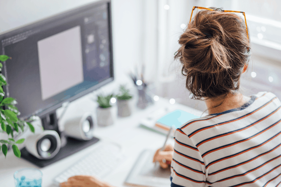 woman sitting in front of a laptop looking out of a window