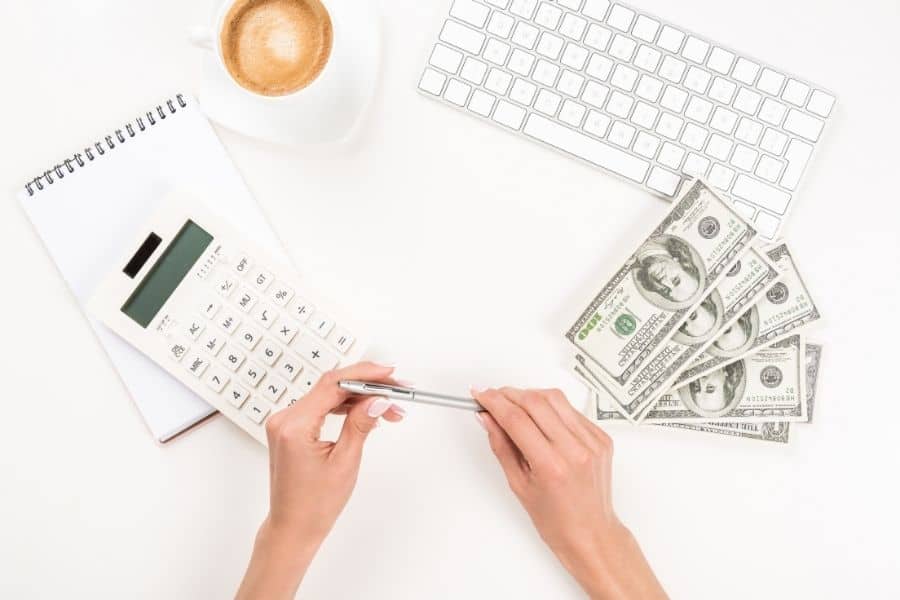 woman holding a pen and looking at a calculator with money