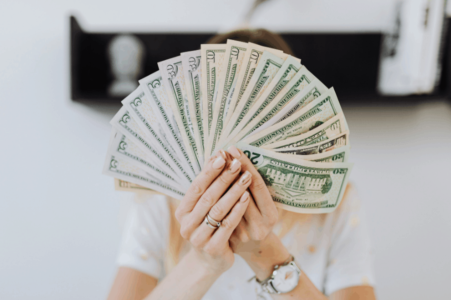 woman holding money in front of her face