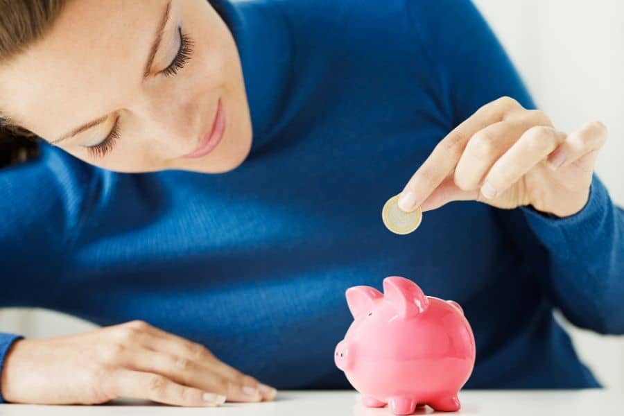 woman adding coins to a pink piggy bank