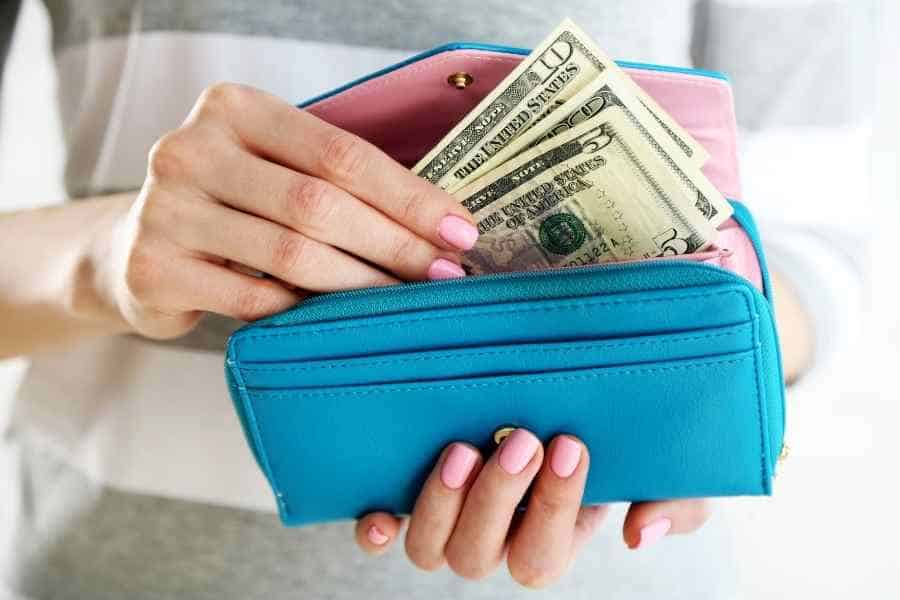 woman putting cash into a blue wallet