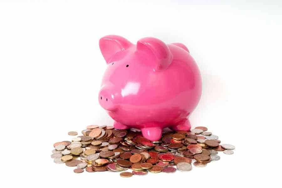 pink piggy bank sitting on a pile of coins