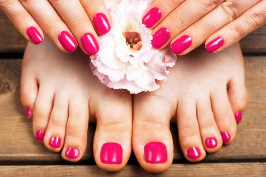 hands holding a pink flower on top of feet with pink toenails