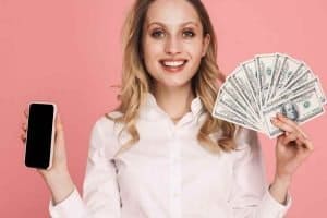 woman holding cash in one hand and a smartphone in the other