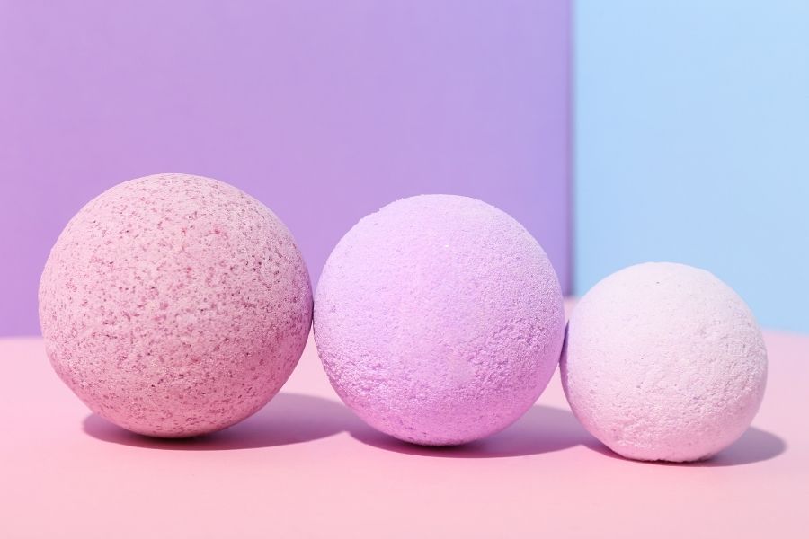 multicolored bath bombs on a pink table