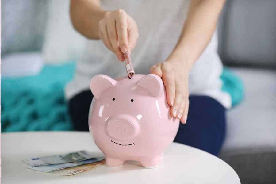 woman adding money to a piggy bank