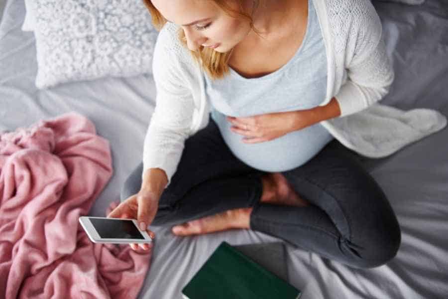 pregnant woman taking surveys on her phone