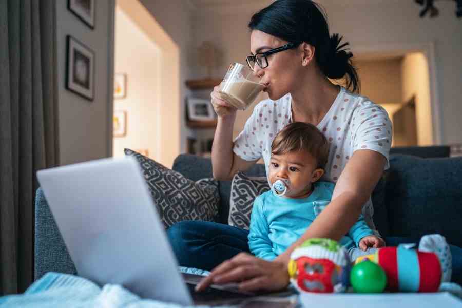 woman looking at a laptop while holding a baby