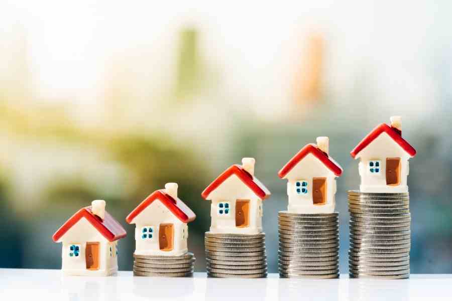 miniature houses sitting on stacks of coins