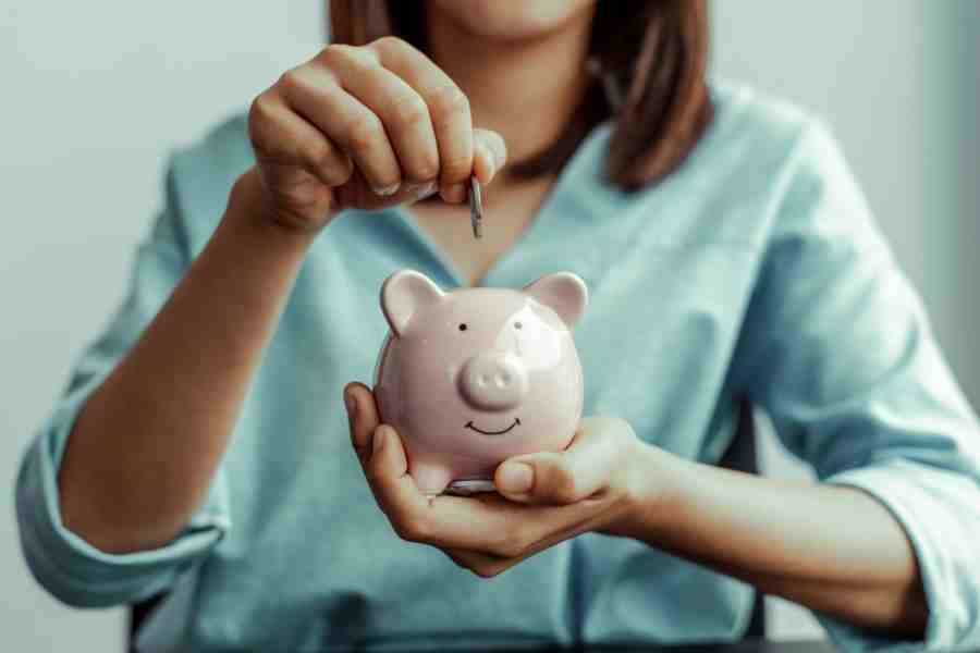 woman adding money to a piggy bank