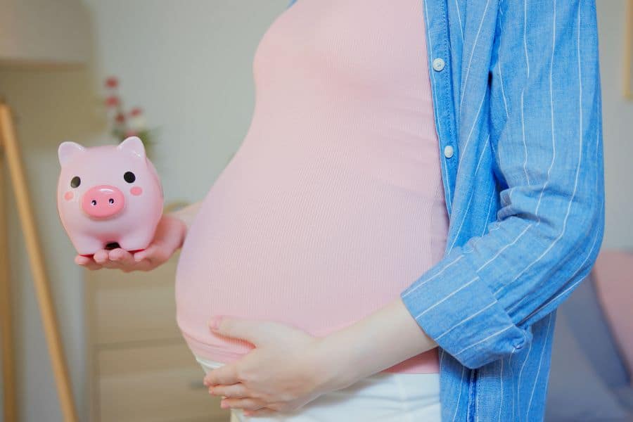 pregnant woman holding a piggy bank