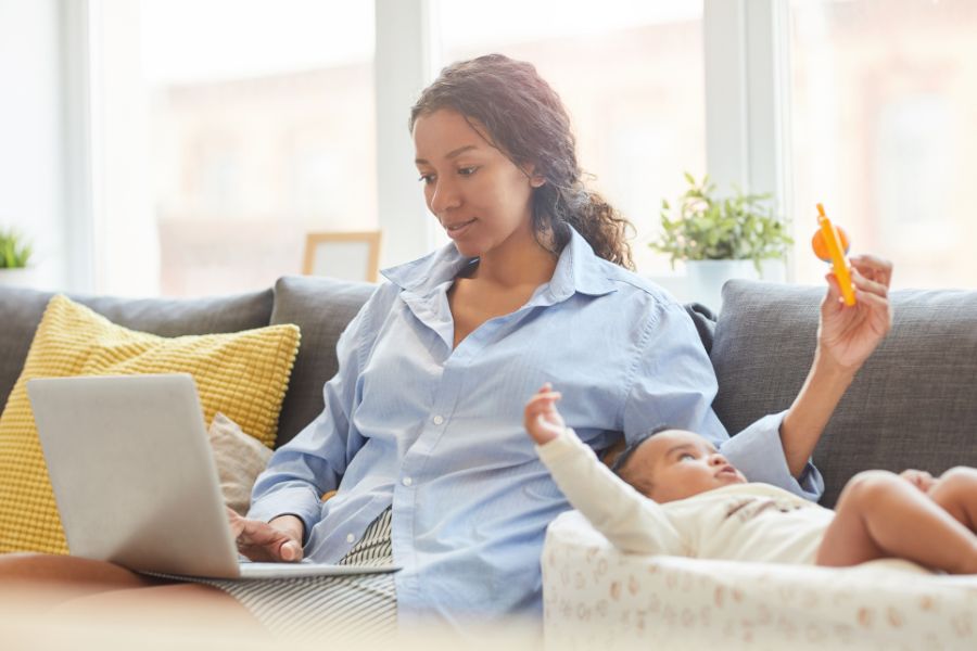 woman working on a laptop with a newborn nearby