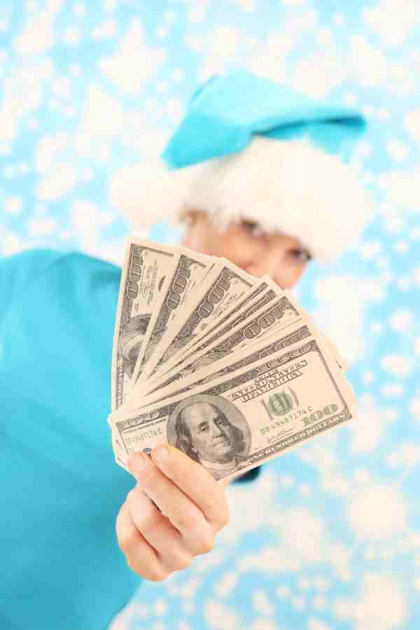 woman wearing a santa hat holding money